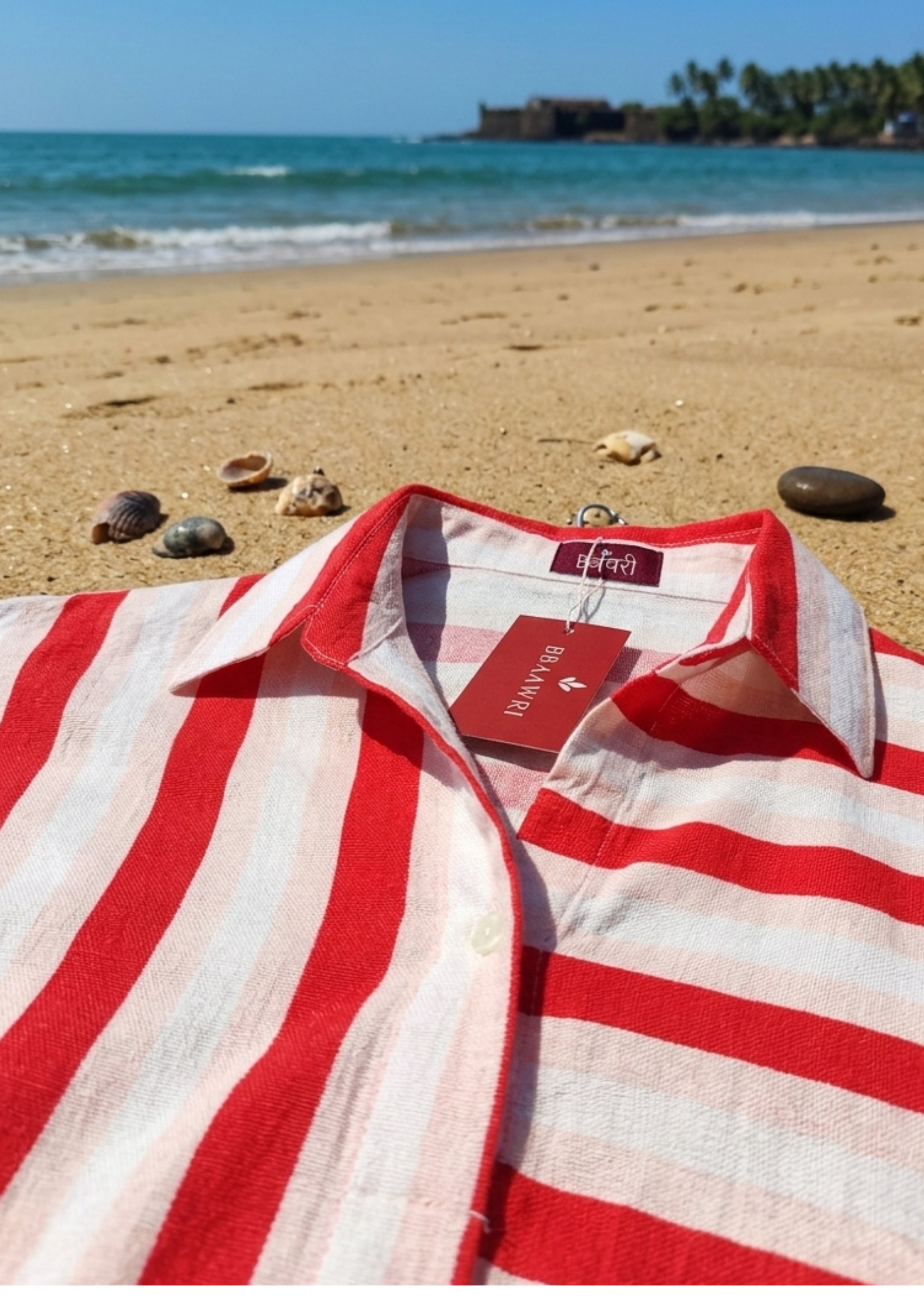 Red and white striped shirt on a beach with ocean and rocks in the background