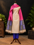 A beige Tussar silk kurta displayed on a mannequin with a bright pink shawl featuring purple and black patterned borders, styled with blue pants against a dark background with plants.