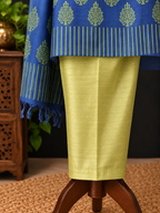 A close-up of a traditional outfit displayed on a stand, featuring a bright yellow-green skirt paired with a royal blue dupatta decorated with gold motifs and stripes.