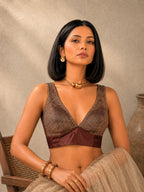 Woman wearing a brown patterned top and beige skirt against a neutral background