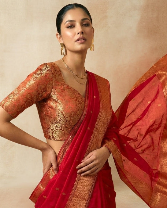 Woman in a red saree with 'ANGIA' text on a beige background
