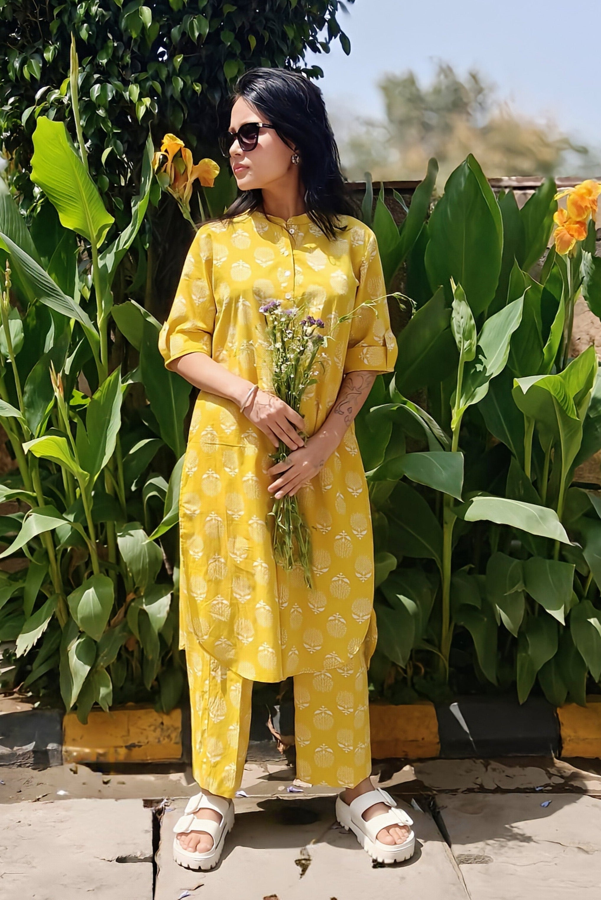 Woman in yellow printed cotton coord set with flowers, styled for summer in a garden.
