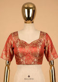 Red and gold blouse on a mannequin against a beige background