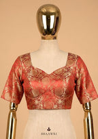 Red and gold blouse on a mannequin against a beige background