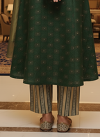 Person wearing a green patterned outfit with striped pants in an indoor setting.