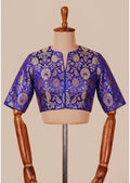 Blue embroidered blouse on a mannequin against a beige background